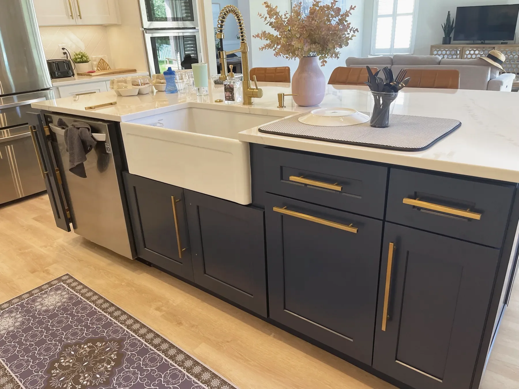 Navy blue shaker island with a white farmhouse sink, brass bar pulls and a gold spring-neck faucet
