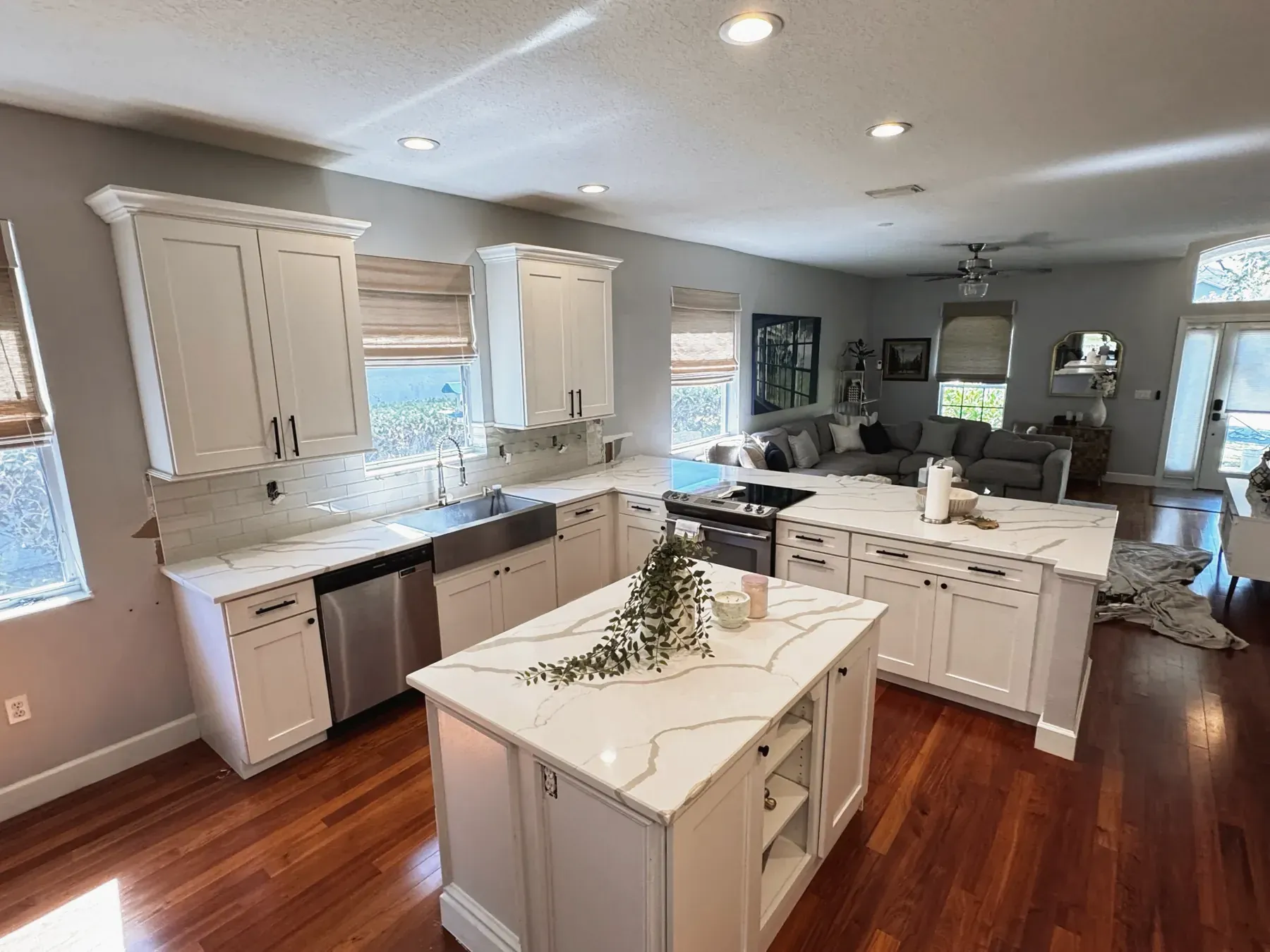 Open-plan kitchen with white cabinets and an island topped with veined stone