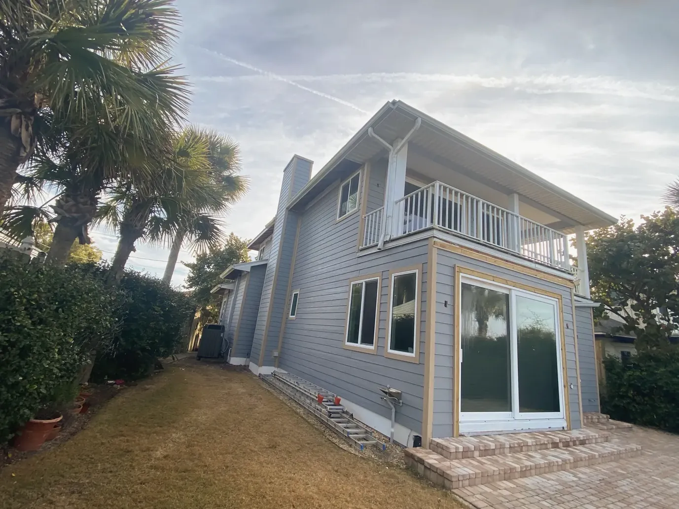 Two-story coastal home with gray siding and a ground-floor sliding glass door