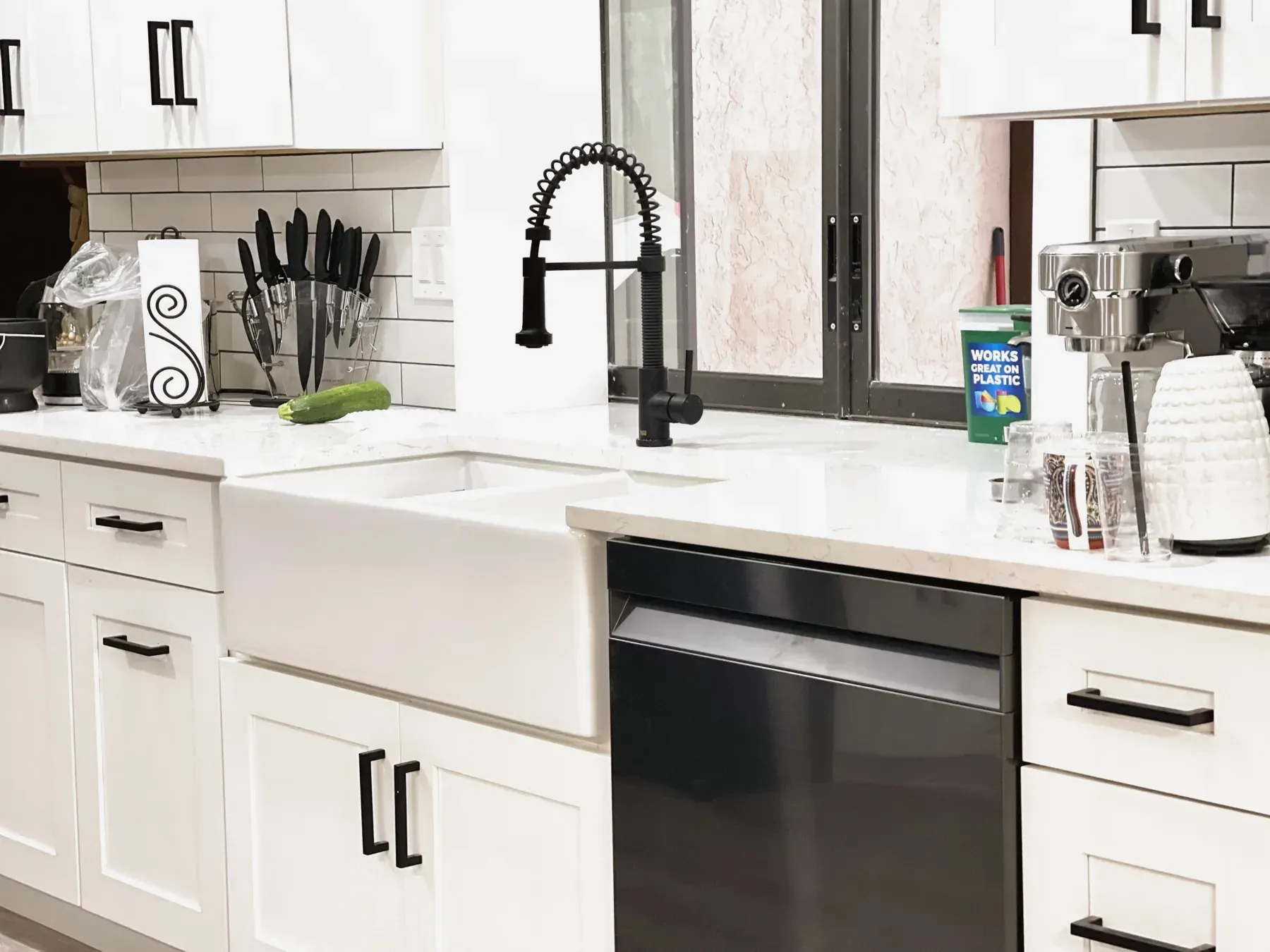 White shaker cabinets with black bar pulls, a white farmhouse sink and a matte black spring-neck faucet