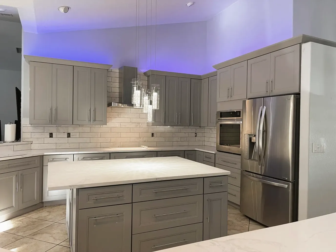 Gray shaker cabinets with white subway tile, an island and stainless appliances