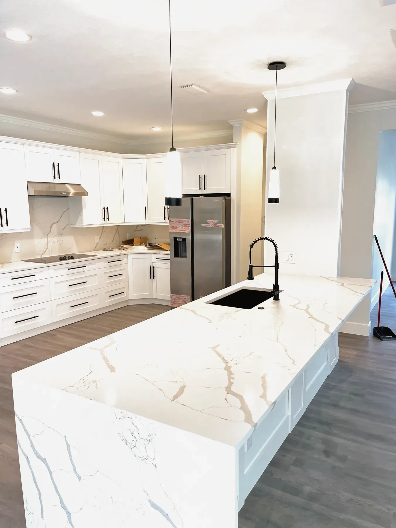 Island with a white stone waterfall edge with gray veining and a black faucet