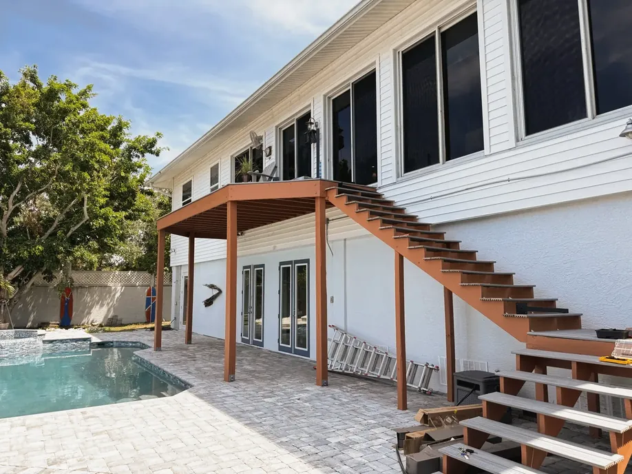 Home exterior with a new wood deck, staircase and pool beyond