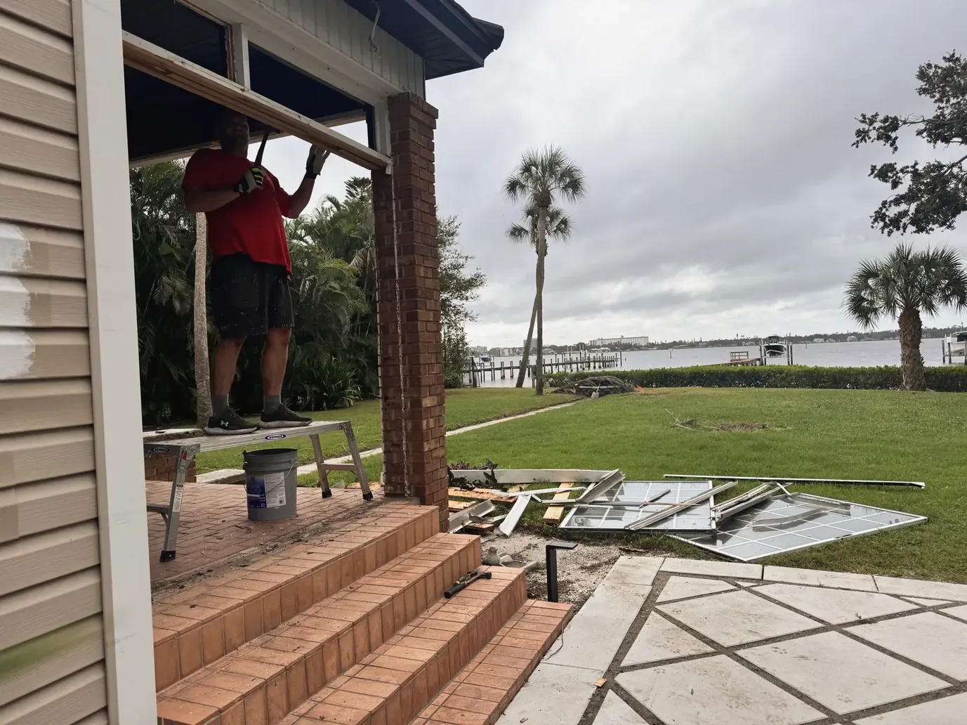 Worker on a brick porch of a waterfront home during a renovation