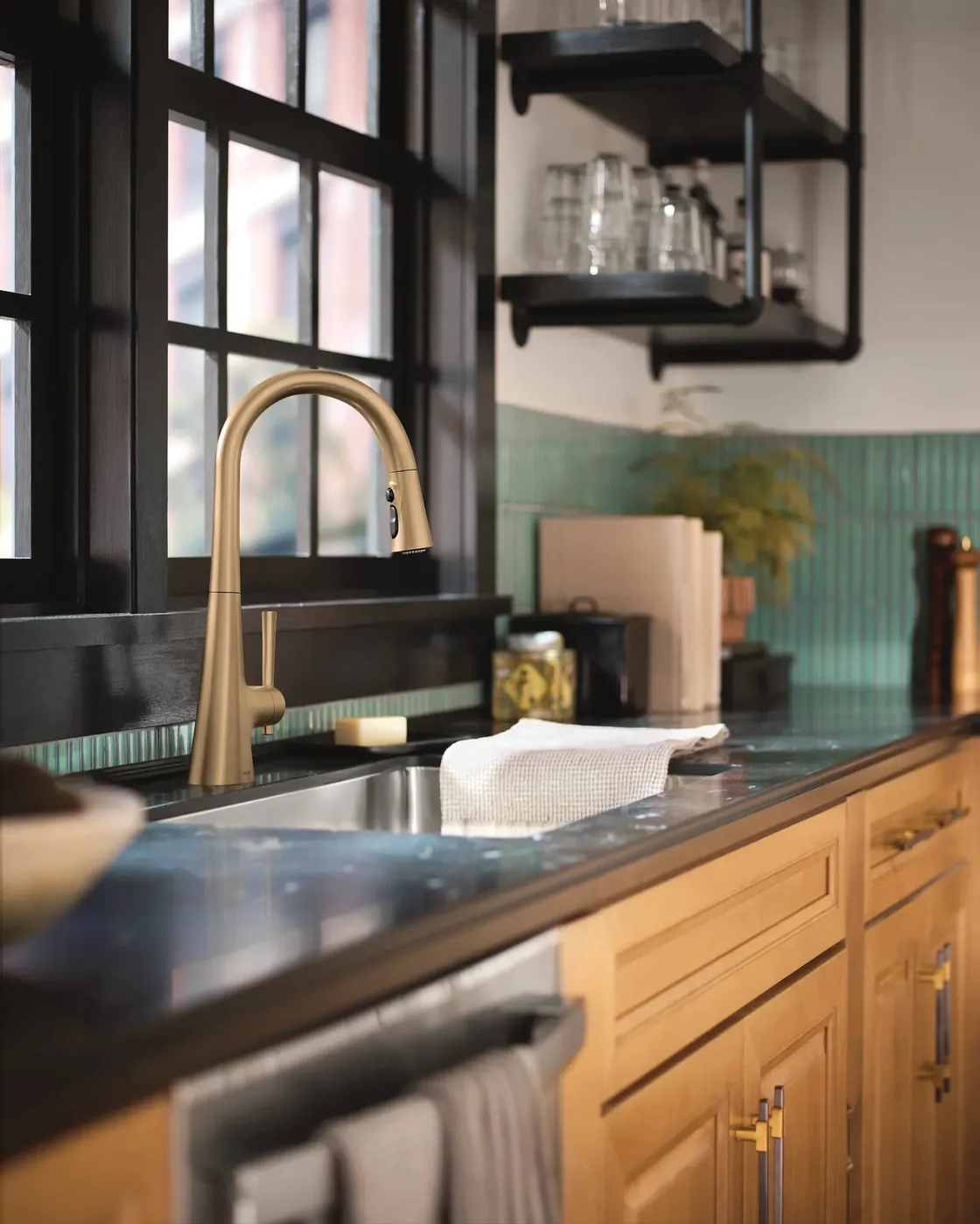 Gold Moen pull-down faucet over an undermount sink in a kitchen with dark cabinets